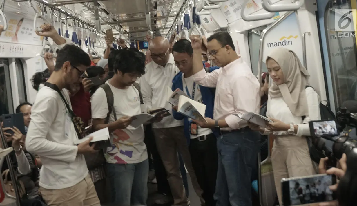 Gubernur DKI Anies Baswedan bersama masyarakat pengguna MRT tengah membaca buku yang disediakan disetiap stasiun MRT di Jakarta, Minggu (8/9/2019). Pemprov DKI Jakarta  meluncurkan ruang baca buku disetiap stasiun MRT untuk menumbuhkan minat baca masyarakat.(Liputan6.com/Angga Yuniar)
