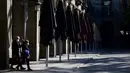 Pasangan yang mengenakan masker berjalan di Barcelona, Spanyol, 23 November 2020. Restoran dan bar di Barcelona serta sekitar Catalonia kembali dibuka setelah tutup selama 40 hari untuk membendung peningkatan kasus virus corona COVID-19. (LLUIS GENE/AFP)