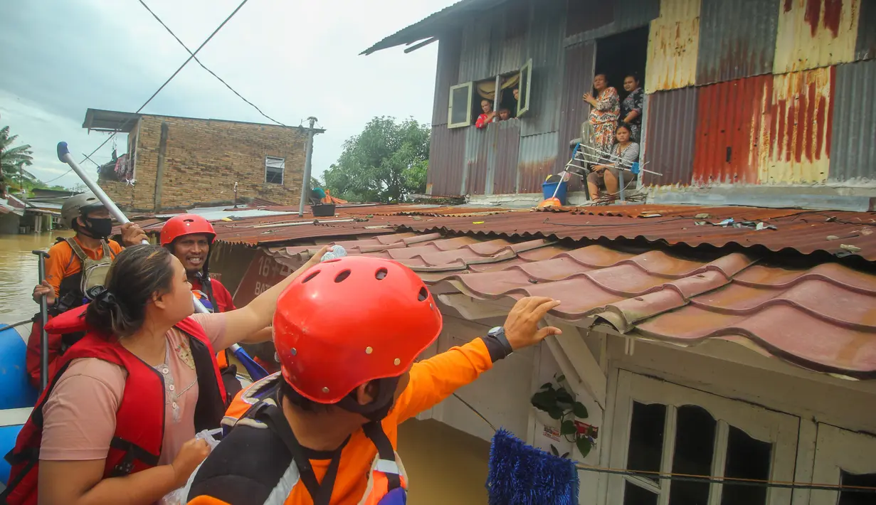 Tim penyelamat mengevakuasi warga di tengah banjir akibat hujan deras semalam di Medan, Sumatera Utara (4/12/2020). Seorang warga Kampung Lalang, Medan, Dean Ramadhan mengatakan, banjir yang terjadi kali ini tergolong parah. (AFP/Rahmad Suryadi)