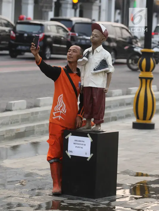 Petugas berselfie di kawasan pedestrian Kali Besar, Kota Tua, Jakarta, Rabu (11/7). Masyarakat sudah bisa mengakses area yang proyek revitalisasinya telah berlangsung sejak 2017 lalu, dan menghabiskan anggaran Rp 260 miliar. (Liputan6.com/Arya Manggala)