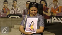 Seorang wanita membawa lukisan korban bom Samarinda Intan Olivia Marbun saat doa bersama di depan Istana Negara, Jakarta, Selasa (15/11). Doa bersama digelar sebagai bentuk dukacita akibat aksi pelemparan bom di Samarinda.(Liputan6.com/Immanuel Antonius)