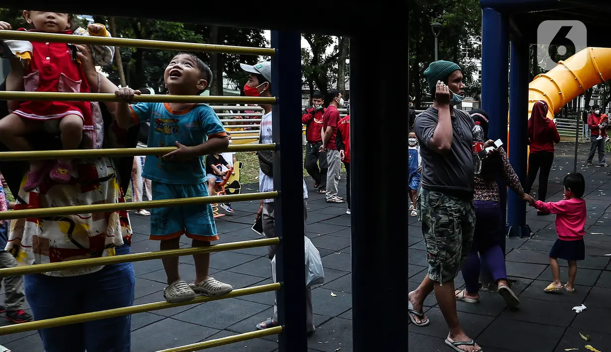Anak-anak didampingi orang tua mereka bermain di Taman Puring, Jakarta, Minggu (9/1/2022). Di tengah ancaman penyebaran covid-19 varian Omicron dan pemberlakukan PPKM level 2, masyarakat tetap melakukan aktivitas pada akhir pekan di luar rumah. (Liputan6.com/Johan Tallo)