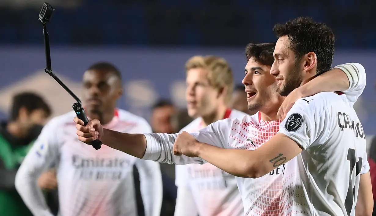 Gelandang AC Milan, Hakan Calhanoglu (kanan) dan Brahim Diaz berselfie usai pertandingan melawan Atalanta pada laga Liga Serie A Italia di stadion Atleti Azzurri d'Italia di Bergamo, Senin (24/5/2021). AC Milan menyudahi absen tujuh tahun di pentas Liga Champions. (AFP/Marco Bertorello)