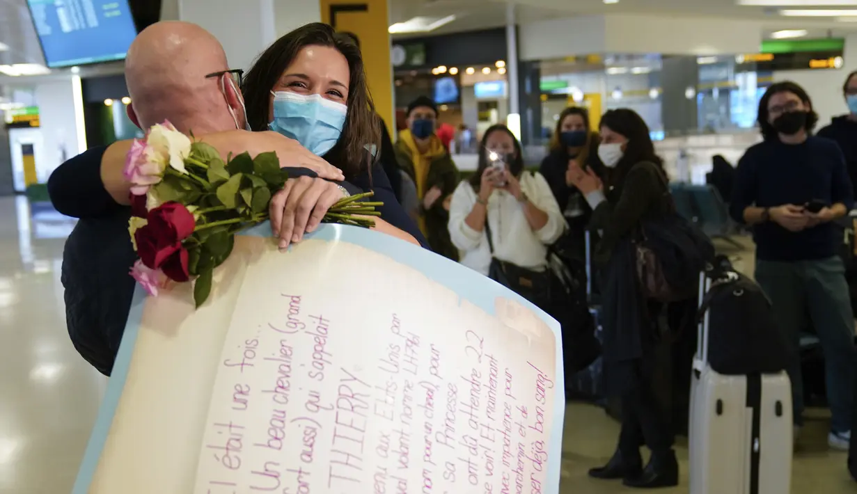 Orang-orang bertepuk tangan saat MaKensi Kastl menyapa pacarnya, Thierry Coudassot, yang tiba dari Prancis di Bandara Internasional Newark Liberty, New Jersey, Senin (8/11/2021). AS membuka kembali perbatasannya untuk pengunjung asing, mengakhiri larangan masuk selama 20 bulan. (AP Photo/Seth Wenig)
