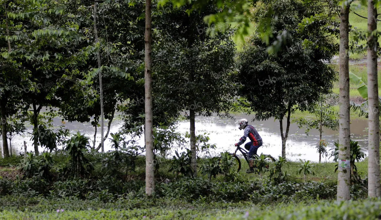 Seorang pebalap melewati lintasan di pinggir danau dalam Indonesian Enduro Series di KTH Bike Park, Puncak, Bogor, (29/5/2016). (Bola.com/Arief Bagus)