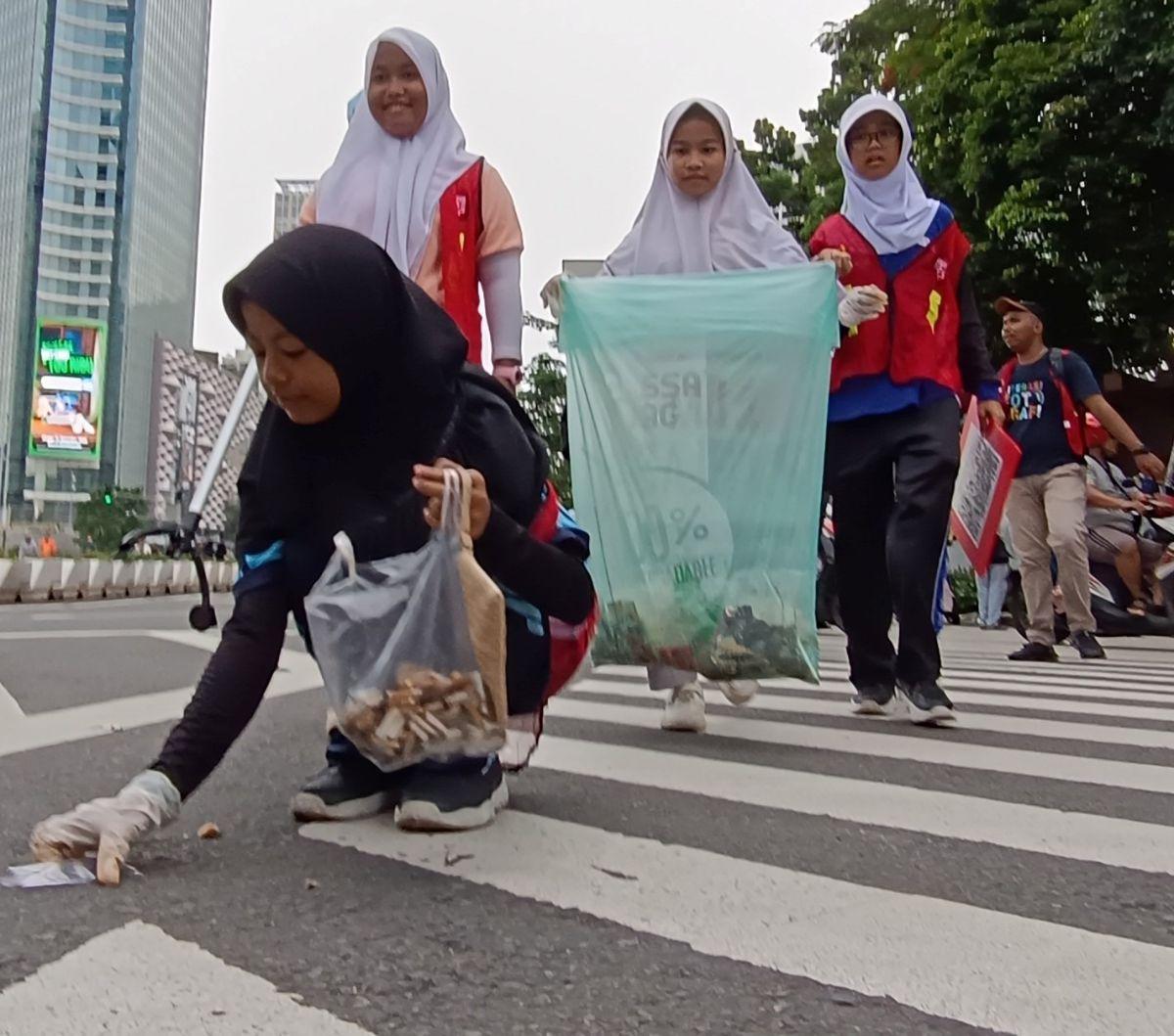 Anak-anak yatim-piatu memunguti sampah-sampah yang ditemukan saat hari bebas kendaraan bermotor (HBKB) atau car free day (CFD) di kawasan Thamrin, Jakarta, Minggu(25/2/2024). Foto: merdeka.com / Arie Basuki
