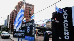 Pejalan kaki milintas di depan tempat cuci mobil yang dihiasi bendera Uruguay di Montevideo (4/7). Uruguay dan Prancis akan bertanding pada babak 8 besar Piala Dunia 2018 di Nizhny Novgorod Stadium, Rusia. AFP Photo/Miguel Rojo)