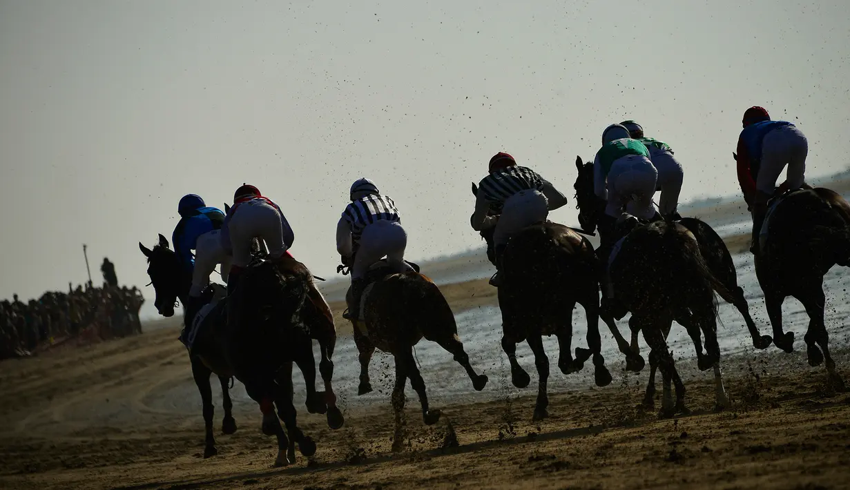 Para peserta saling balap saat mengikuti lomba pacuan kuda pantai tahunan di Sanlucar de Barrameda, dekat Cadiz, Spanyol (17/8). (AFP Photo/Cristina Quicler)