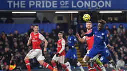 Striker Chelsea, Tammy Abraham, berebut bola dengan bek Arsenal, Shkodran Mustafi, pada laga Premier League pekan ke-24 di Stamford Bridge, London, Rabu (22/1). Arsenal tahan imbang Chelsea 2-2. (AFP/Ben Stansall)
