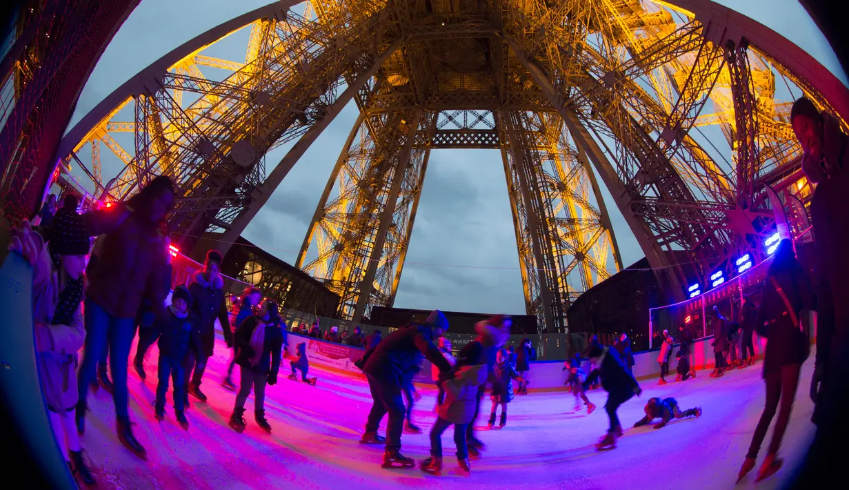 Sejumlah wisatawan menikmati keseruan bermain ice skating di sebuah arena yang dibuka di lantai 1 Menara Eiffel, Paris, 19 Desember 2016. Wahana seluncur es ini memiliki luas sekitar 185 meter persegi di ketinggian 57 meter. (AFP PHOTO/JOEL SAGET)