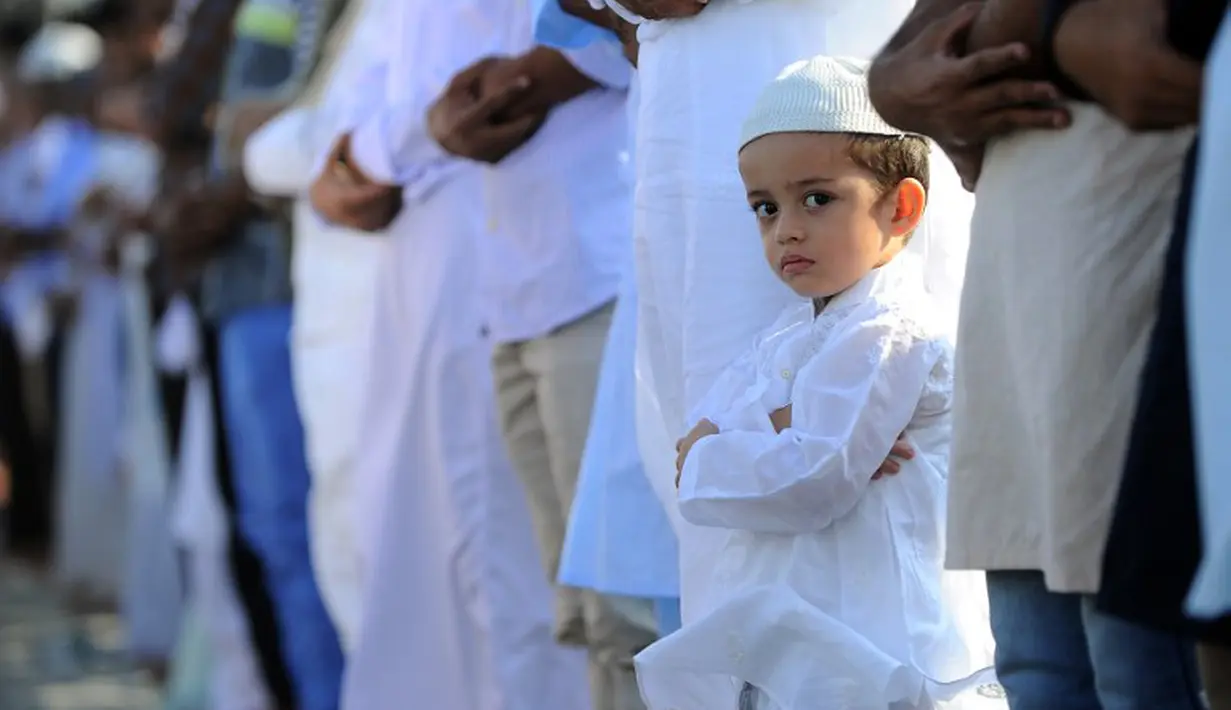 Tahu dirinya akan difoto, bocah India ini melirik sang juru foto saat salat id tengah berlangsung, Hyderabad, India, Senin (6/10/2014) (AFP Photo/Noah SEELAM) 