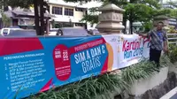 Seoerang pria memasang spanduk untuk acara perpajangan SIM A dan C secara gratis yang bertepat dengan acara Kartini Run 2018. (istimewa)