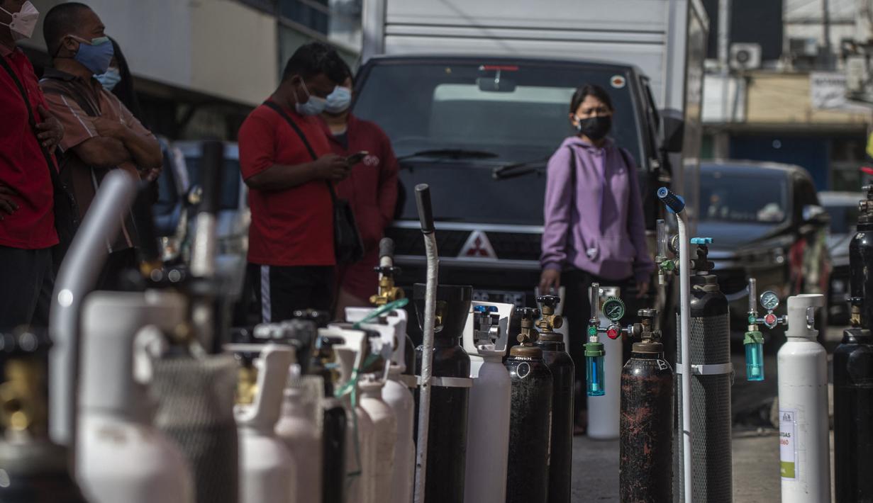 Warga mengantre untuk mengisi ulang tabung oksigen di stasiun pengisian di kota Surabaya, Kamis (15/7/2021). Di Surabaya, masih banyak permintaan isi ulang oksigen, baik tabung kecil 0,5–1 meter kubik hingga ukuran besar 6–7 meter kubik. (Juni Kriswanto / AFP)