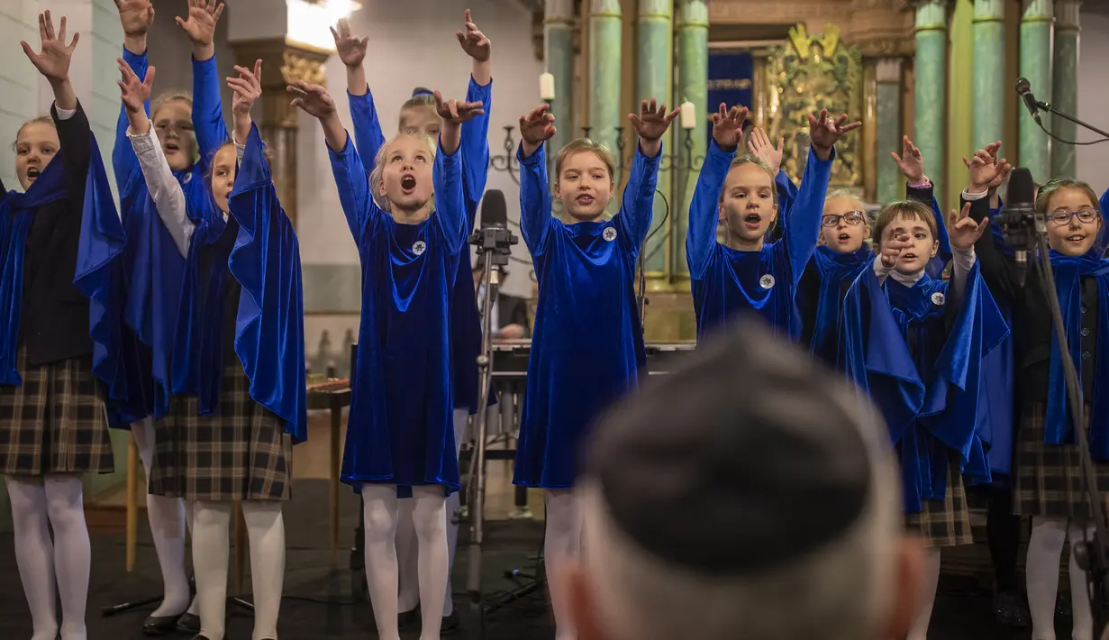 Gadis-gadis bernyanyi selama hari libur Yahudi Hanukkah di Sinagog di Vilnius, Lithuania, Minggu (28/11/2021). Perayaan tahunan komunitas malam pertama Hanukkah kembali dengan kapasitas penuh tahun ini setelah perayaan dibatasi pada tahun 2020 karena pandemi virus corona. (AP Photo/Mindaugas Kulbis)