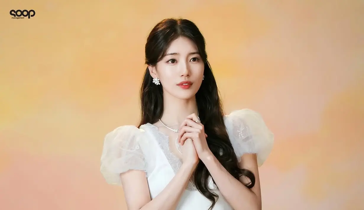 Penampilan Suzy disempurnakan dengan gaun putih beraksen puff sleeve yang memberikan kesan dreamy dan anggun.Detail lace dan potongan leher berbentuk V semakin mempertegas kesan elegan. Aksesori minimalis berupa anting bunga dan kalung berkilauan menjadi pelengkap sempurna untuk penampilannya. [@skuukzky/@management_soop].