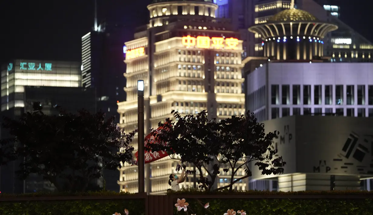 <p>Seorang anggota tim medis mengibarkan bendera pada malam pencabutan penguncian COVID-19 di Shanghai, Selasa (31/5/2022). Pihak berwenang Shanghai mengatakan mereka akan mengambil langkah besar pada Rabu menuju pembukaan kembali kota terbesar di China setelah dua bulan penguncian COVID-19. (AP Photo/Ng Han Guan)</p>