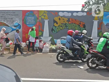 Pejalan kaki dan warga melintasi mural yang berisi pesan ajakan untuk menjaga lingkungan di Jalan Tambak, Manggarai, Jakarta, Selasa (11/2/2020). Mural tersebut bertujuan mengingatkan bahwa permasalahan lingkungan merupakan masalah serius yang harus dihadapi bersama. (Liputan6.com/Herman Zakharia)