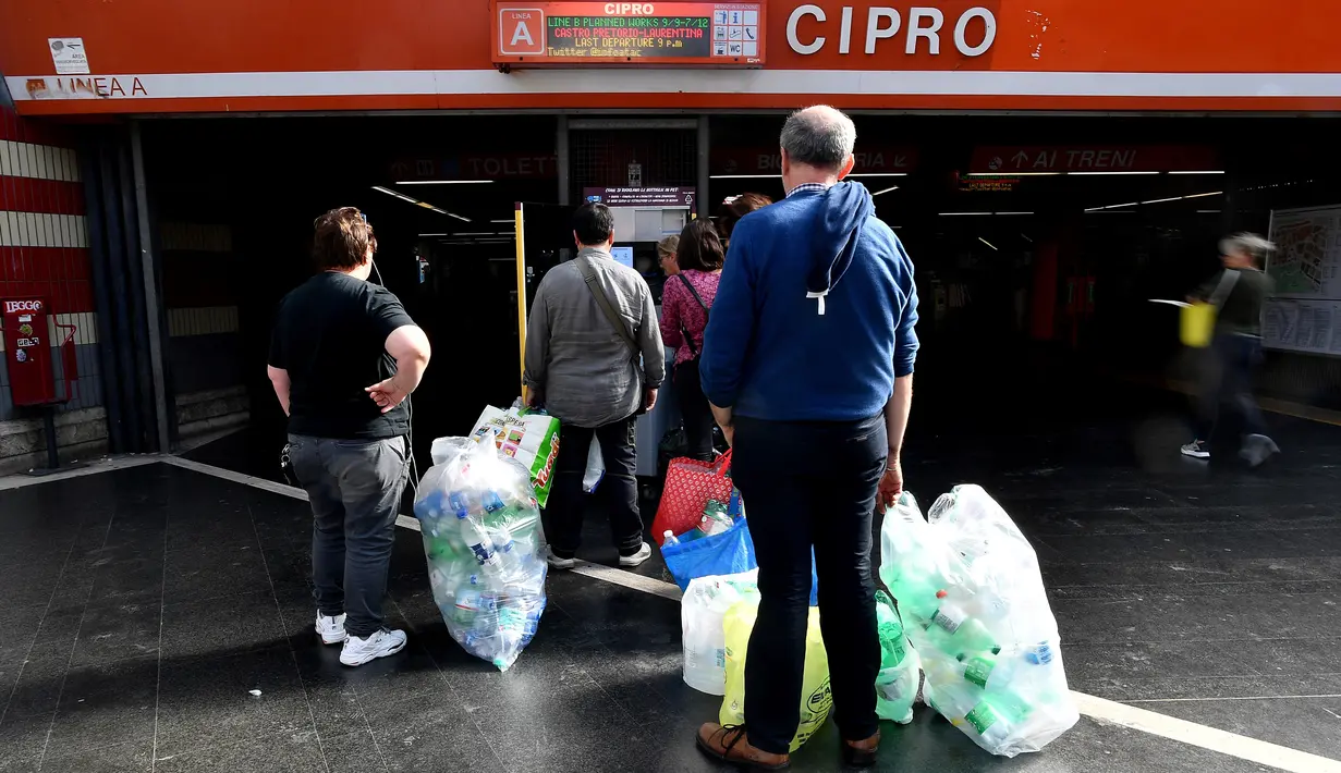 Penumpang antre menukarkan sampah botol plastik dengan tiket kereta menggunakan mesin daur ulang di stasiun metro bawah tanah Cipro, Roma, Selasa (8/10/2019). Warga harus memasang aplikasi di ponsel untuk mendapatkan barcode tiket elektronik setiap kali menukarkan botol plastik. (Tiziana FABI/AFP)