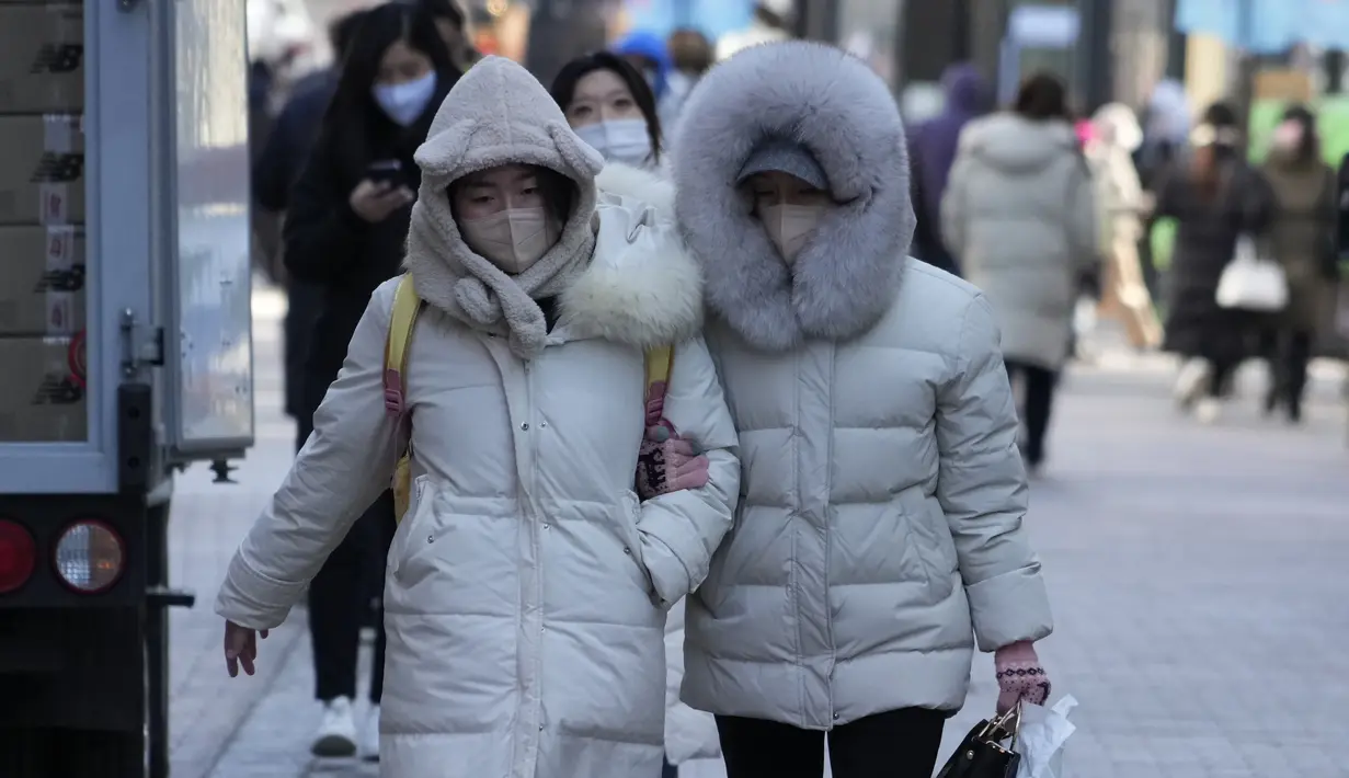 Para perempuan berjalan di jalan saat kondisi cuaca dingin di Seoul, Korea Selatan, Rabu (25/1/2023). Ribuan pelancong memadati bandara kecil di pulau Jeju Korea Selatan pada hari Rabu untuk mendapatkan penerbangan setelah penundaan karena kendala angin kencang dan salju tebal. (AP Photo/Ahn Young-joon)