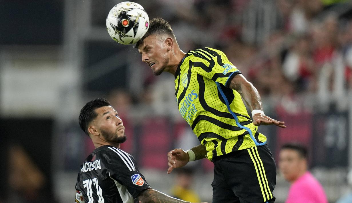 Bek Arsenal, Ben White menyundul bola di atas gelandang MLS All-Stars, Luciano Acosta pada laga pramusim 2023/2024 di Washington DC, Amerika Serikat, Kamis (20/7/2023) pagi WIB. (AP Photo/Alex Brandon)