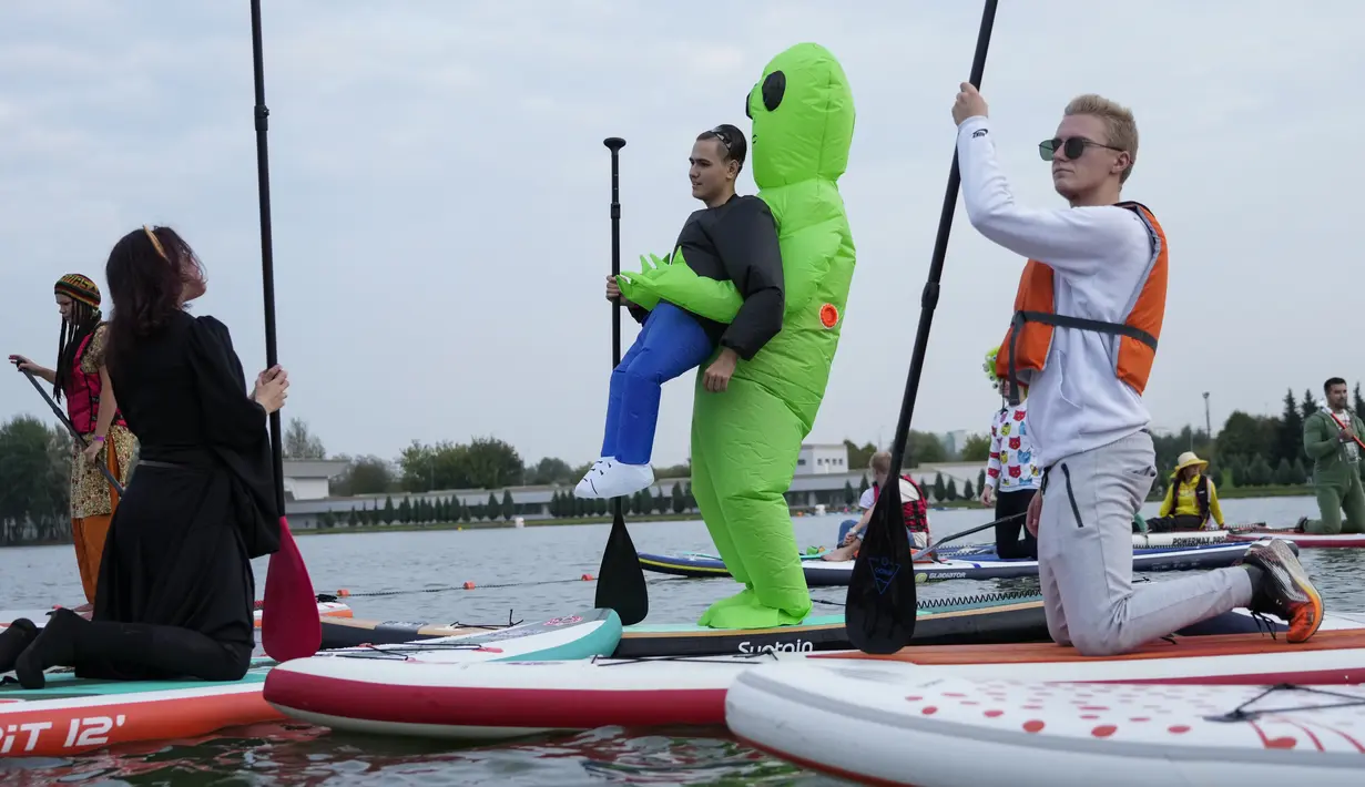 Orang-orang mengarahkan papan SUP mereka selama festival dayung berdiri (stand up paddle) di kanal dayung Olimpiade Krylatskoye, Moskow, Rusia, Minggu (12/9/2021). Selain menjadi agenda rutin pariwisata, kegiatan tersebut juga dimaksud untuk memopulerkan SUP ke masyarakat luas. (AP/Pavel Golovkin)