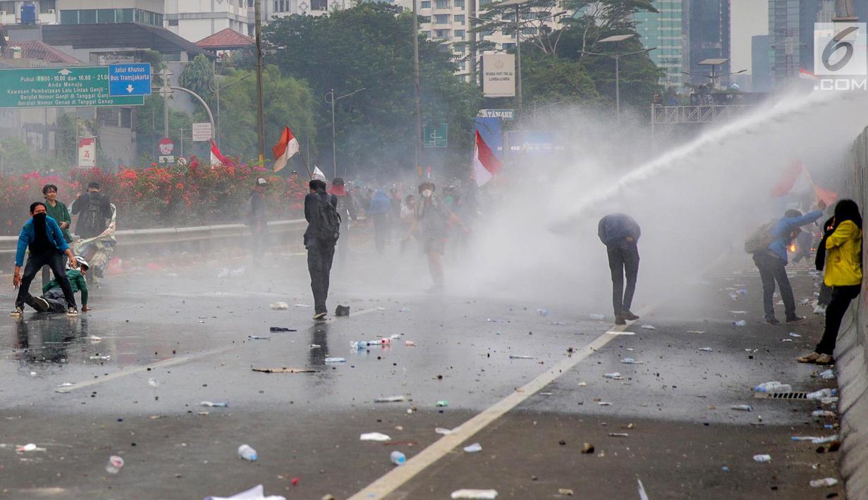 Mahasiswa mendapat semprotan air dari kendaraan water cannon polisi dalam demonstrasi menolak pengesahan RUU KUHP dan revisi UU KPK di depan Gedung DPR, Jakarta, Selasa (24/9/2019). Semprotan water cannon dan tembakan gas air mata memaksa mahasiswa mundur. (Liputan6.com/Faizal Fanani)
