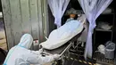 Pekerja memindahkan jenazah korban corona dari wadah (kontainer) berpendingin ke dalam peti mati di luar kamar mayat Rumah Sakit Thammasat, utara Bangkok, Rabu (4/8/2021). Jenazah Covid-19 yang membludak di kamar mayat rumah sakit, mengingatkan pada bencana tsunami 2004. (Lillian SUWANRUMPHA/AFP)