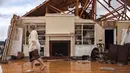 Jenny Bullard membawa sepasang sepatu dari rumahnya yang rusak akibat badai besar yang menghantam Negara Bagian Georgia, Amerika Serikat, Minggu (22/1). Puluhan orang mengalami luka-luka dan sedang dilarikan ke rumah sakit terdekat (AP Photo/Branden Camp)