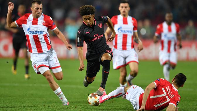 Pemain Arsenal, Reiss Nelson (tengah) menghindar dari terjangan pemain  Belgrade Crvena Zvezda, Marko Gobeljic pada laga grup H Liga europa di Stadion Rajko Mitic, (19/10/2017). Arsenal menang 1-0. (AFP/Andrej Isakovic)