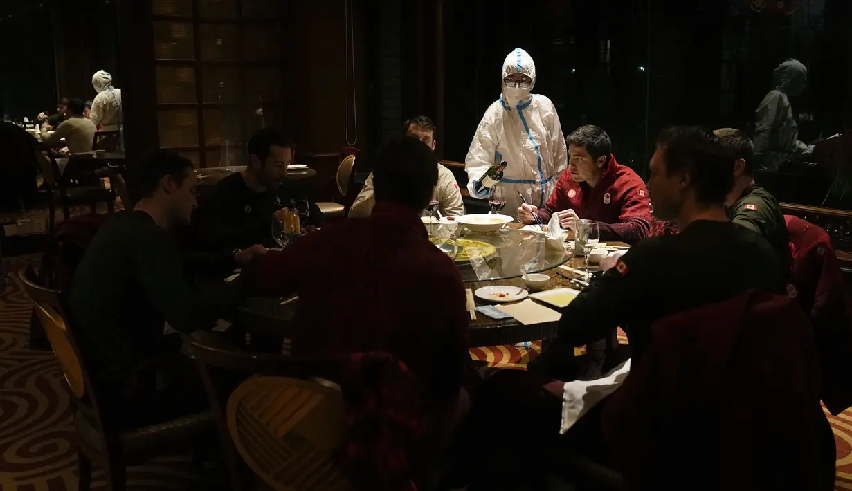 Seorang pramusaji dengan pakaian pelindung diri atau hazmat menyajikan meja di sebuah restoran di dalam Hotel Shangri-La pada Olimpiade Musim Dingin 2022, 16 Februari 2022, di Beijing. (AP Photo/Jae C.Hong)