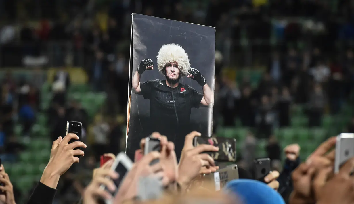Penggemar mengangkat poster juara kelas ringan UFC, Khabib Nurmagomedov saat kedatangannya di Stadion Anzhi Arena, Makhachkala, Rusia, Senin (8/10). Nama Khabib menjadi terkenal setelah dirinya berhasil mengalahkan Conor McGregor. (AFP/Vasily MAXIMOV)