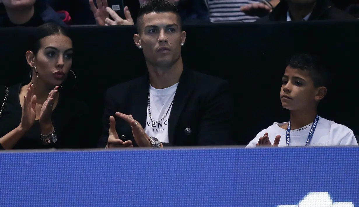 Pemain Juventus, Cristiano Ronaldo bersama sang kekasih, Georgina Rodriguez dan anaknya, Cristiano Jr menyaksikan Novak Djokovic menghadapi John Isner pada laga tenis dunia, ATP Finals 2018, di O2 Arena, London, Senin (12/11). (AP /Tim Ireland)