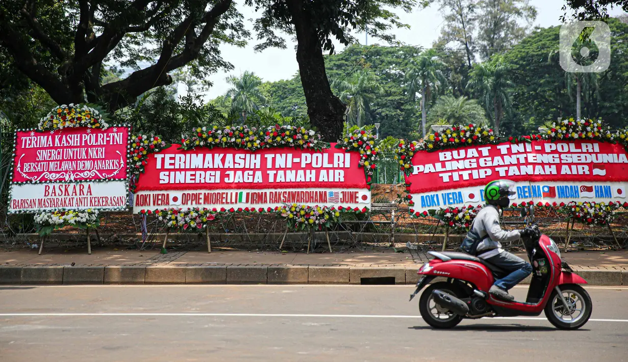 Kendaraan melintasi karangan bunga yang menghiasi kawasan Patung Kuda, Jakarta, Kamis (15/10/2020). Karangan bunga tersebut merupakan apresiasi masyarakat kepada TNI-Polri yang telah menjaga keamanan saat demo. (Liputan6.com/Faizal Fanani)