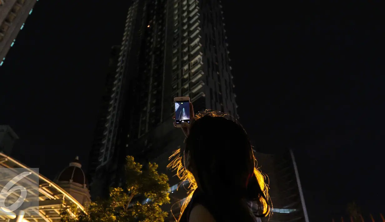 Warga mengabadikan titik api yang masih tersisa di Gedung Neo Soho, Jakarta Barat, Rabu (9/11). Gedung Neo Soho sempat terbakar hebat hampir di setiap lantainya. (Liputan6.com/Faizal Fanani)