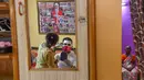 Relawan pekerja sosial Ashok Kurmi melukis wajahnya sebelum menyebarkan kesadaran tentang COVID-19 di daerah kumuh Mumbai pada 2 Juni 2021. Kurmi turun tangan memerangi virus Corona di daerah kumuh Mumbai menggunakan aksesori yang tidak biasa, yaitu kostum badut. (INDRANIL MUKHERJEE/AFP)