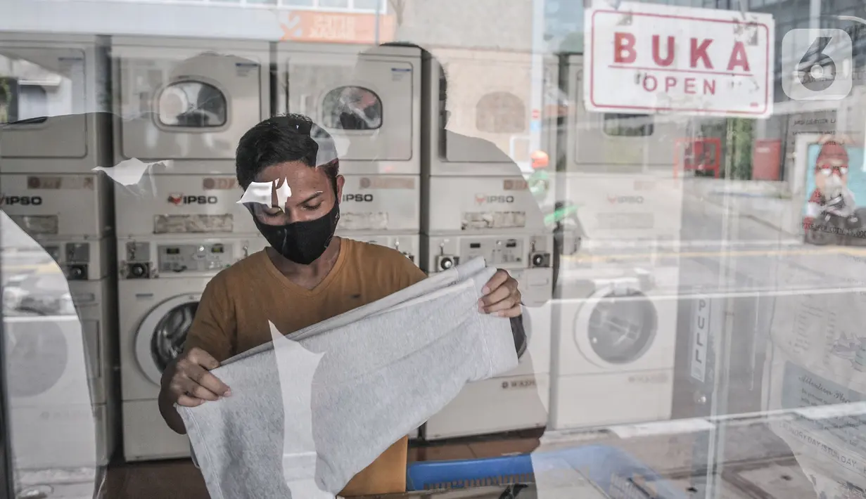 Pekerja merapikan pakaian pelanggan yang dititipkan di Jaksa Clean Coin Laundry, Jalan Jaksa, Jakarta, Kamis (1/4/2021). Seorang pekerja mengungkapkan sebelum pandemi biasanya menerima rata-rata 10 pelanggan dalam sehari, namun kini merosot menjadi 4 pelanggan per hari. (merdeka.com/Iqbal S Nugroho)