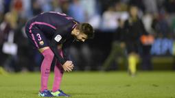 Bek Barcelona, Gerard Pique, tertunduk lesu usai timnya dikalahkan Celta Vigo. Kekalahan ini menjadi yang kedua bagi Barca musim ini di ajang La Liga. (AFP/Miguel Riopa)