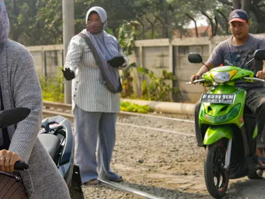 Neng Mulyani atau Bu Neng (tengah) mengatur lalu lintas di perlintasan kereta yang berada di Batuceper, Tangerang, Jumat (15/11/2019). Selama 8 tahun, wanita paruh baya ini mengabdikan waktunya untuk menjaga perlintasan. (Liputan6.com/Magang/Andika Zulfikar)