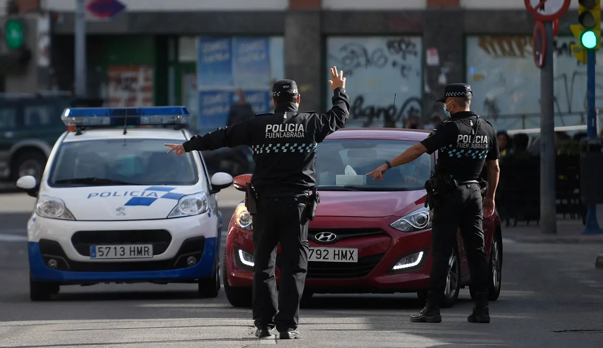 Petugas polisi setempat mengontrol pergerakan orang di sebuah pos pemeriksaan lalu lintas di kota Fuenlabrada yang tertutup sebagian, di wilayah Madrid (22/9/2020). Pemerintah daerah Madrid telah memberlakukan penguncian sebagian di beberapa daerah berpenduduk padat. (AFP/Oscar Del Pozo)