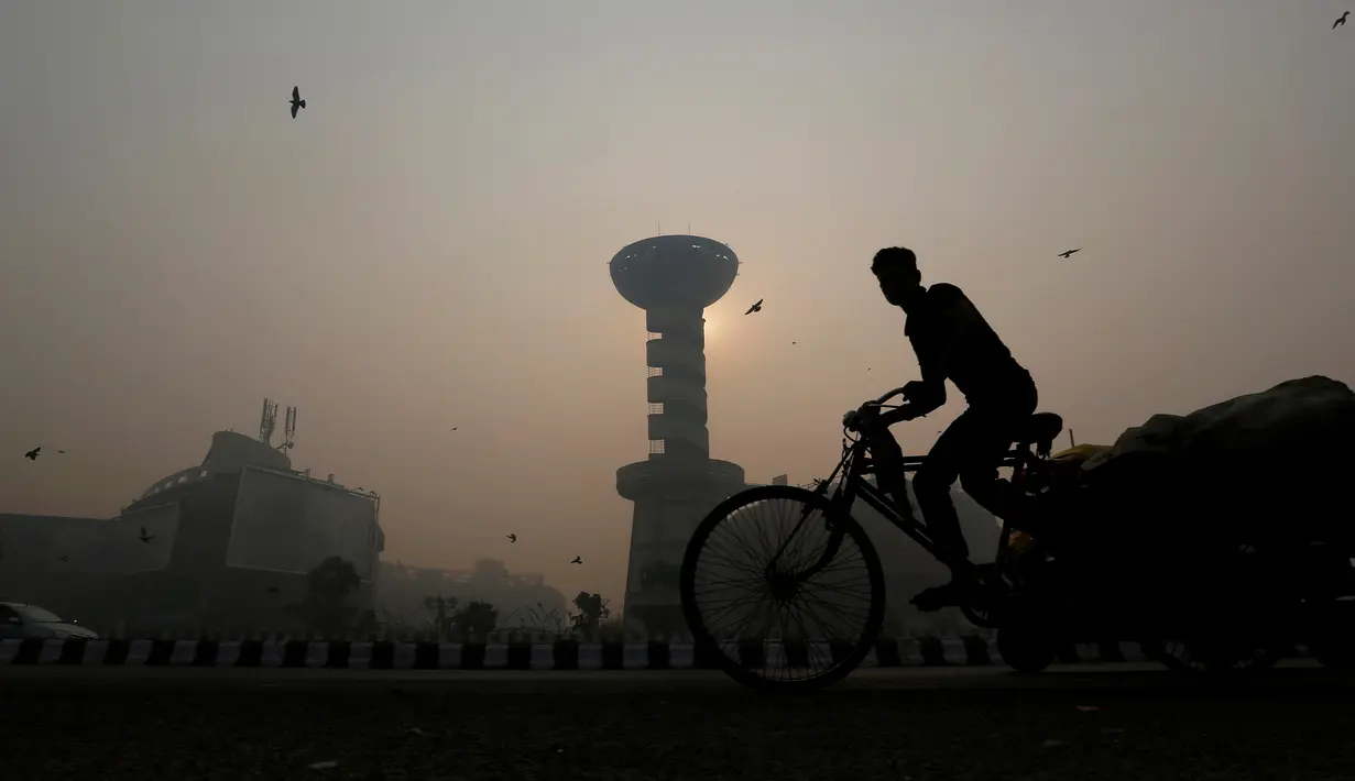 Warga mengedarai becak sepeda melewati sebuah pusat perbelanjaan ditengah kabut tebal polusi perayaan Diwali di New Delhi, India (31/10). Dalam mengurangi polusi ini pemerintah setempat akan memasang pemurni udara. (Reuters/Adnan Abidi)
