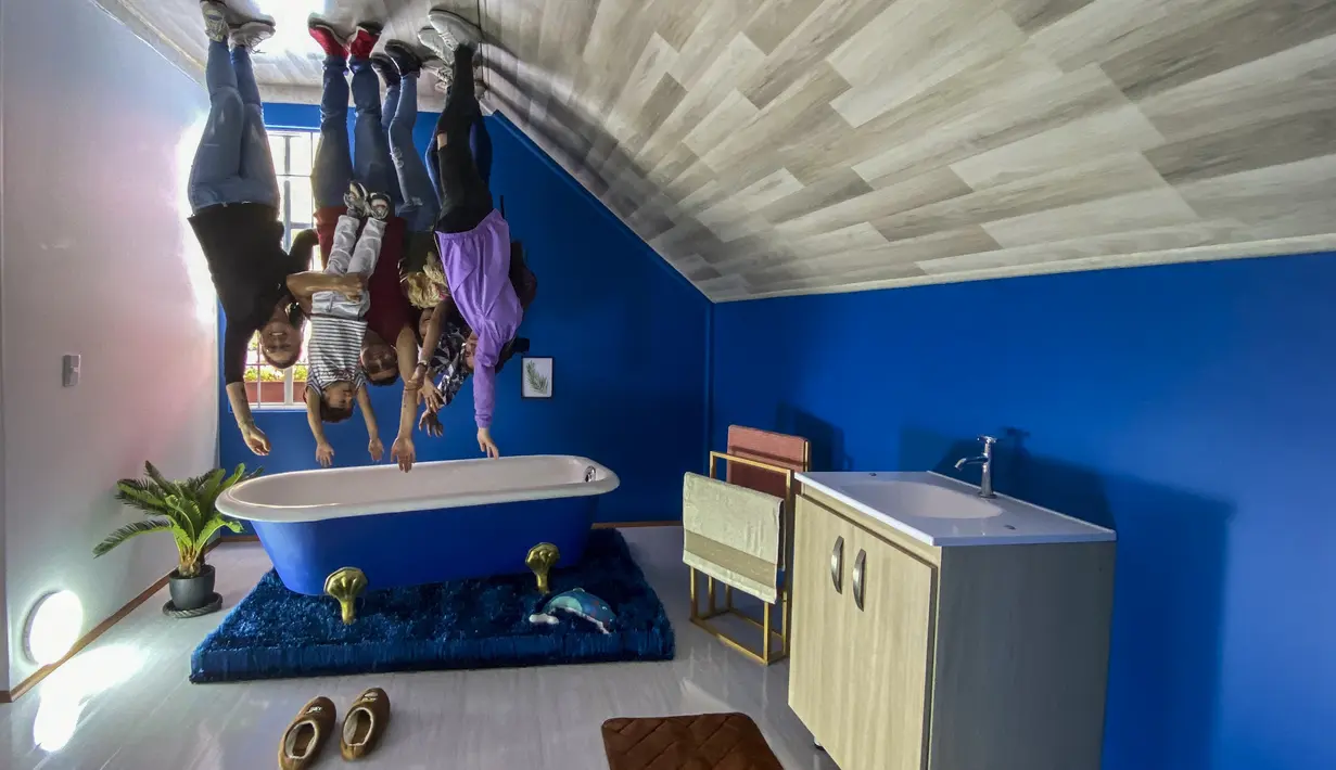 Orang-orang berpose untuk foto di dalam rumah terbalik, di Guatavita, dekat Bogota, pada 29 Januari 2022. Rumah terbalik itu sendiri mulai dibangun selama pandemi dan baru rampung pada awal tahun 2022 ini. (Juan BARRETO / AFP)