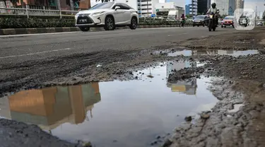 Sejumlah pengendara saat melintas dekat jalan yang berlubang di kawasan Gatot Subroto, Jakarta, Kamis (18/11/2021). Memasuki musim hujan yang turun hampir setiap hari membuat sejumlah ruas jalan rusak dan tergenang sehingga mengakibatkan jalan berlubang. (Liputan6.com/Johan Tallo)