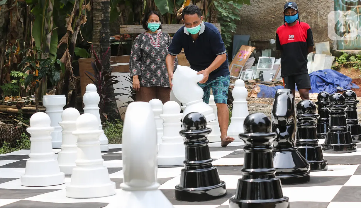 Warga bermain catur raksasa sambil menunggu waktu berbuka puasa di Pondok Betung, Tangerang Selatan, Kamis (14/5/2020). Tinggi bidak catur 50-86 cm dengan diameter sekitar 35 cm terbuat dari bahan viber glass dengan luas lapangan 4,8m x 4,8m. (Liputan6.com/Fery Pradolo)