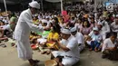 Pemuka agama Hindu memberikan air suci saat upacara Tawur Kesanga di Pura Aditya Jaya, Rawamangun, Jakarta, Jumat (16/3). Upacara Tawur Kesanga digelar sebagai rangkaian perayaan Hari Raya Nyepi Tahun Baru Saka 1940. (Liputan6.com/Arya Manggala)