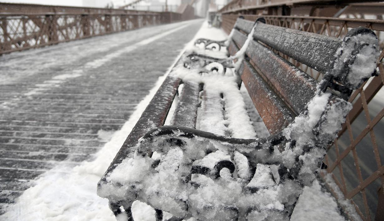 Sebuah bangku di Jembatan Brooklyn, New York tertutup salju, Selasa (14/3). Badan Meteorologi Amerika Serikat (NWS) menetapkan status darurat untuk negara bagian New York dan New Jersey yang terancam dilanda badai musim dingin. (ANGELA WEISS / AFP)
