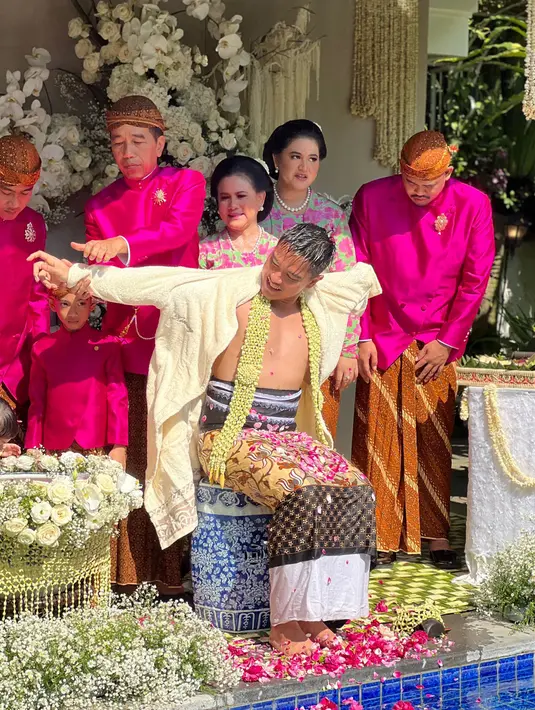 Presiden Joko Widodo atau Jokowi memasangkan pakaian terhadap sang anak Kaesang Pangarep saat prosesi siraman jelang pernikahannya di kediaman, Sumber, Kota Surakarta, Jawa Tengah, Jumat (9/12/2022). Ketujuh air siraman disatukan dalam satu tempat untuk digunakan dalam prosesi siraman. (Tim Media Pernikahan Kaesang-Erina)