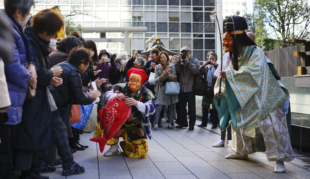 Seniman mengenakan topeng Ebisu, dewa para nelayan, yang disebut sebagai salah satu dari Tujuh Dewa Keberuntungan di Jepang selama Festival Konpira di kuil Kotohiragu di distrik bisnis Toranomon di Tokyo (10/1/2020). (AP Photo/Eugene Hoshiko)