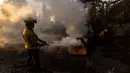 Petugas pemadam berupaya memadamkan api di lokasi jembatan yang terbakar di perbukitan Big Pines dekat Wrightwood, California. pada tanggal 12 September 2024. (ETIENNE LAURENT/AFP)