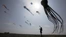 Seorang wanita melihat layang-layang dalam Varvara Kite Fest di Desa Varvara, pesisir Laut Hitam, Bulgaria, Jumat (27/8/2021). Penyelenggara Varvara Kite Fest Andrey Kulev mengatakan bahwa menerbangkan layang-layang seperti melepaskan semua masalah Anda di langit. (AP Photo/Valentina Petrova)