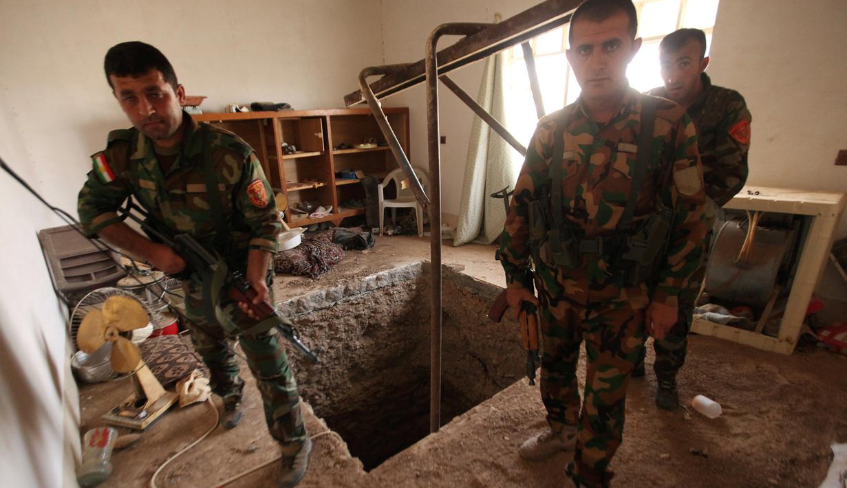Tiga pasukan Peshmerga bersenjata berjaga di terowongan tempat persembunyian militan ISIS selama operasi penyerangan di Mosul, Irak (19/10). Penemuan terowongan milik militan ISIS itu terdapat di dalam bangunan. (REUTERS/Azad Lashkari)